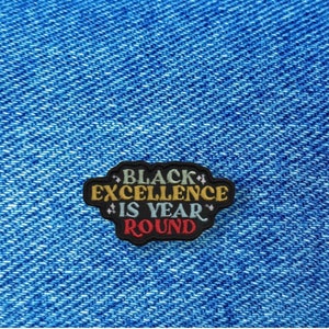 May include: Black Excellence is Year Round embroidered patch on a blue denim background.