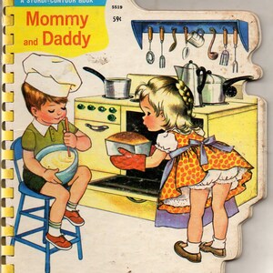 May include: Vintage children's book titled "Mommy and Daddy." The cover features a colorful illustration of two children in a kitchen. One child is mixing batter, and the other is taking bread out of the oven. The book has a spiral binding.