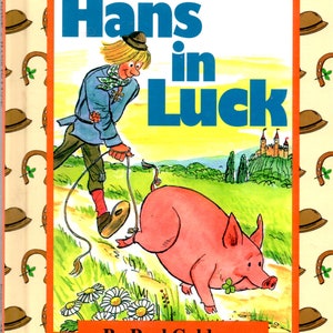 May include: A book cover with an illustration of a man named Hans walking a pig. The book title is "Hans in Luck" and the author is Paul Galdone. The cover is decorated with a pattern of brown hats and horseshoes.