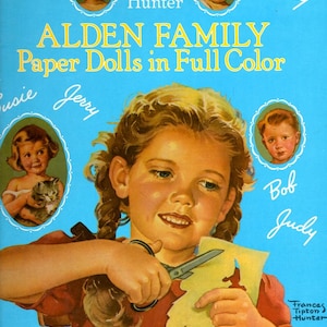 May include: A vintage book cover featuring a girl cutting out paper dolls. The cover is blue with white lettering that reads "Alden Family Paper Dolls in Full Color". The girl has blonde hair and is wearing a red dress. She is holding a pair of scissors and a sheet of paper with a paper doll cutout.