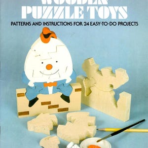 May include: A book cover with the title "Wooden Puzzle Toys" and a cartoon illustration of a wooden puzzle toy in the shape of a person. The book cover is blue and the illustration is in shades of brown, orange, and white. The book cover also includes the text "Patterns and Instructions for 24 Easy-to-Do Projects".