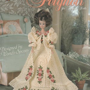 May include: A crochet pattern booklet titled Stephanie's Peignoir for Fashion Dolls, designed by Wanda Spears. The cover features a fashion doll wearing a cream-colored, floor-length crocheted peignoir gown adorned with small pink and green floral accents.