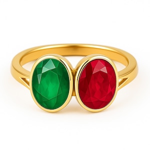 Może przedstawiać: Złoty pierścionek z dwoma owalnymi kamieniami szlachetnymi: zielonym szmaragdem i czerwonym rubinem. Kamienie są umieszczone obok siebie, tworząc kontrast z polerowaną złotą obrączką. Projekt pierścionka jest prosty, ale elegancki.