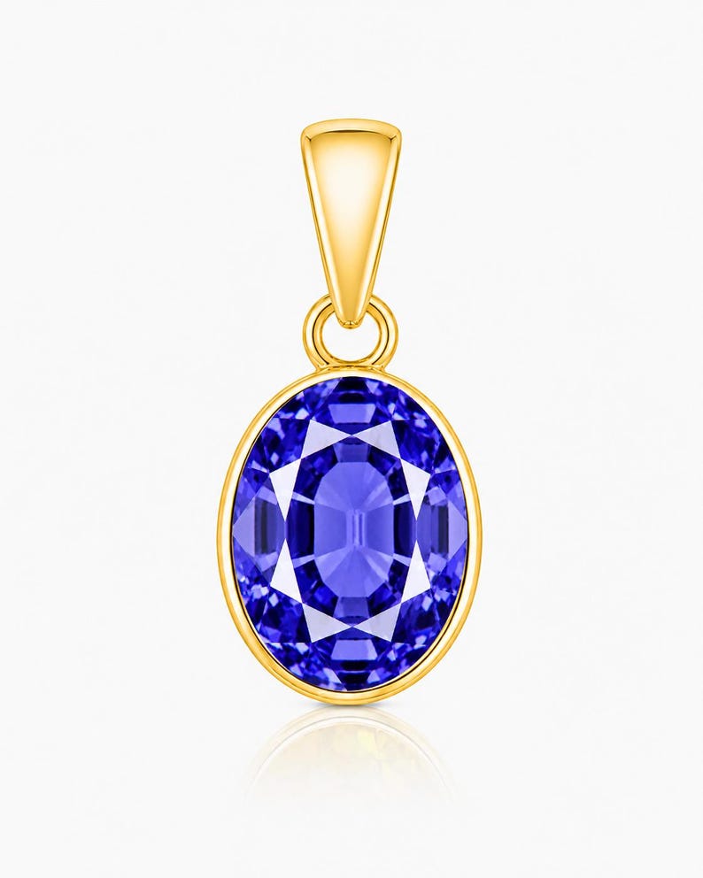 May include: A gold pendant featuring an oval-shaped, faceted blue gemstone set in a smooth gold bezel. The pendant includes a tapered gold bail at the top, designed for attachment to a chain, showcasing a polished finish and vibrant blue colour.