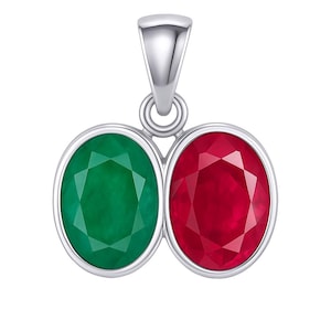 Może przedstawiać: Srebrny wisiorek z dwoma owalnymi kamieniami szlachetnymi: żywym zielonym szmaragdem i głębokim czerwonym rubinem. Kamienie są osadzone w polerowanej srebrnej ramie, z pętlą na łańcuszek u góry.