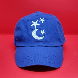 May include: A royal blue baseball cap with a white crescent moon and three white stars embroidered on the front.