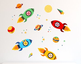 May include: A set of colorful rocket ship wall decals with animal faces. The rockets are flying through space with planets, stars, and a comet. The decals are perfect for a child's bedroom or playroom.