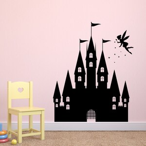 Puede incluir: Silueta negra de un castillo de cuento de hadas con un hada volando por encima. El castillo tiene m&uacute;ltiples torres y una puerta. El hada sostiene una varita m&aacute;gica y tiene alas. La imagen est&aacute; en una pared rosa.