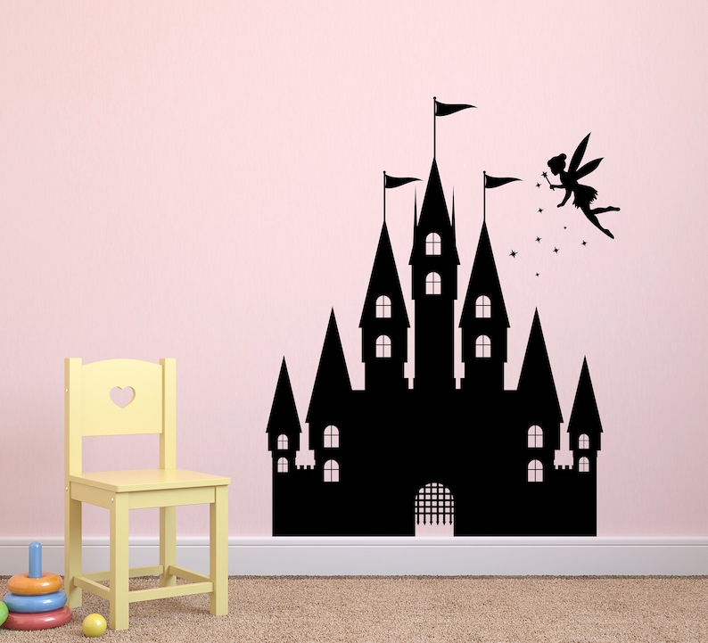 Puede incluir: Silueta negra de un castillo de cuento de hadas con un hada volando por encima. El castillo tiene m&uacute;ltiples torres y una puerta. El hada sostiene una varita m&aacute;gica y tiene alas. La imagen est&aacute; en una pared rosa.
