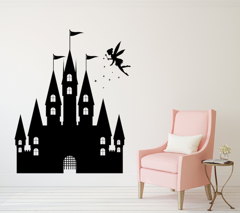 Puede incluir: Pegatina de pared en silueta negra de un hada volando hacia un castillo con estrellas. El castillo tiene m&uacute;ltiples torres y ventanas. La pegatina est&aacute; en una pared blanca con un sill&oacute;n rosa en primer plano.