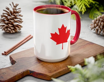 May include: A white coffee mug with a red Canadian maple leaf design. The mug is filled with coffee and has a red handle. The mug is sitting on a wooden chopping board.