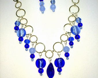 Striking Handmade Necklace and Earring Set. Shades of Blue Glass Beads dangle from Silver Circles.