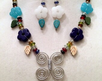 Hand Formed Butterfly in silver tone wire. Dark blue, Aqua and White Glass Flowers.