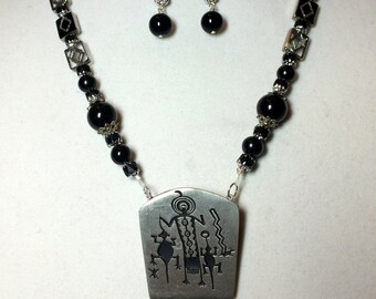 Handmade Necklace and Earring Set. Pendant is a Vintage 1998 Urban Fetishes Pin. Beads are Black Glass and Clear Glass trimmed in Silver.