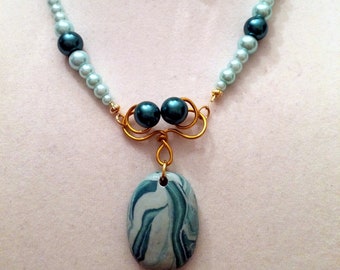 Handmade necklace and  earring set. Shades of teal. Polymer clay oval and  glass pearls. Hand formed gold-tone wire swirls.