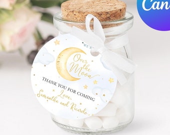 May include: A white favor tag with blue and gold accents featuring a crescent moon and stars. The tag reads "We're Over the Moon. Thank you for coming. Love, Samantha and Ricardo."