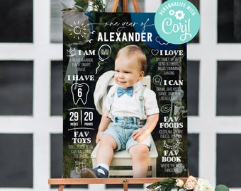 May include: A chalkboard style first birthday sign for a boy named Alexander. The sign features a photo of the boy, his age, height, weight, favorite toys, foods, and books. The sign is personalized with the name "Coryl".