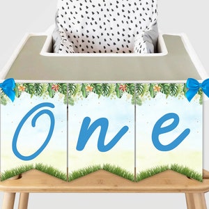Puede incluir: Una pancarta de silla alta de temática de selva en azul y verde con la palabra "Uno" en letras cursivas azules. La pancarta tiene lazos azules en cada extremo.