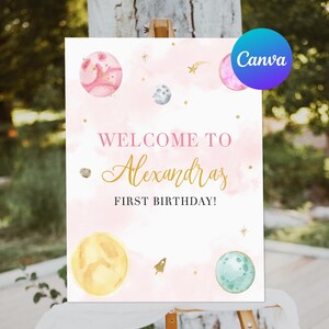 Puede incluir: Un cartel de bienvenida rosa y blanco con purpurina dorada y planetas de acuarela. El cartel dice "¡Bienvenido a Alexandra's First Birthday!"