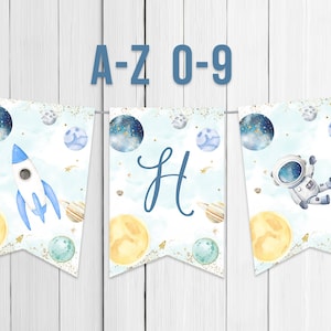 Puede incluir: Una pancarta azul y blanca con temática espacial. La pancarta tiene un cohete, un astronauta, planetas y estrellas. La pancarta dice "A-Z 0-9" en letras azules.