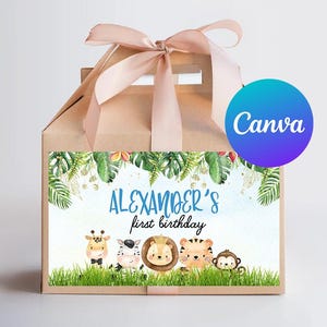 Puede incluir: Una caja de regalo marrón con una cinta marrón claro y una etiqueta con temática de animales de la selva. La etiqueta presenta una pancarta azul con el texto "ALEXANDER'S first birthday" e ilustraciones de una jirafa, una cebra, un león, un tigre y un mono.