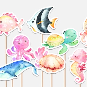 以下が含まれることがあります： カラフルな水彩画の海の生き物のカップケーキトッパー9個セット。トッパーは、ピンクのタコ、青いクジラ、黄色と緑の亀、ピンクのタツノオトシゴ、ピンクとオレンジのイカ、ピンクとオレンジの魚、白と黒のエンゼルフィッシュ、ピンクとオレンジの貝殻を特徴としています。