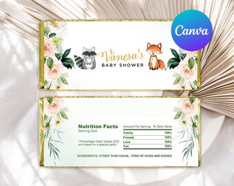 May include: A white chocolate bar wrapper with a floral design and gold accents. The wrapper features a raccoon and a fox illustration, along with the text "Vanesa's Baby Shower". The back of the wrapper has a nutrition facts label with a playful list of ingredients.