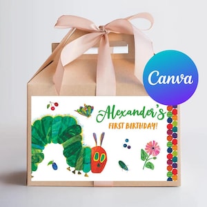 May include: A brown cardboard favor box with a green, red, and yellow caterpillar design. The box has a white label with the text "Alexander's First Birthday!" and a pink bow on top.