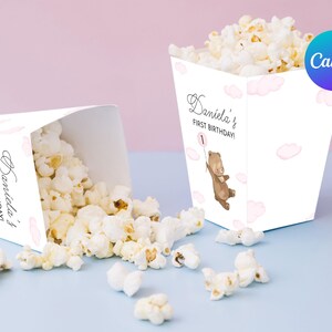 Peut inclure: Boîtes à popcorn blanches décorées de nuages roses et d'un ours brun tenant un ballon. Les boîtes sont décorées du texte "Daniela's First Birthday!"
