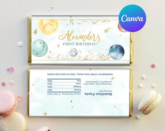 May include: A blue and gold chocolate bar wrapper with a space theme. It says "Alexander's First Birthday!" and has planets, stars, and a rocket ship. The back of the wrapper has a nutrition facts label with a fun, lighthearted message.