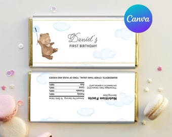 May include: A chocolate bar wrapper with a blue and white design featuring clouds and a bear holding a number one balloon. The text "Daniel's First Birthday!" is printed on the wrapper.