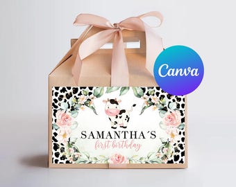 May include: A brown favor box with a pink ribbon and a sticker featuring a cow with pink accents, floral designs, and the text "Samantha's first birthday".