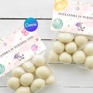 Puede incluir: Bolsas de regalo para fiestas de temática de astronauta rosa y azul con fondo blanco y purpurina dorada. Las bolsas tienen una etiqueta que dice "Alexandra cumple un año" con un astronauta de dibujos animados y planetas.