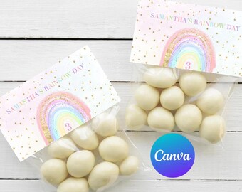 May include: A pink and white favor bag with a rainbow and gold glitter design. The bag has the text "Samantha's Rainbow Day" and the number "3" printed on it. The bag is filled with white chocolate candies.