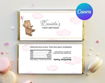 May include: A chocolate bar wrapper with a pink and white design featuring a cartoon bear holding a balloon. The wrapper says "Daniela's First Birthday!" and includes a nutrition facts label.