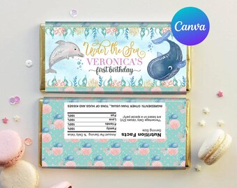 May include: Under the Sea Veronica's first birthday chocolate bar wrapper with a blue whale and a dolphin on a blue and green background with seashells. The wrapper also includes a nutrition facts label.