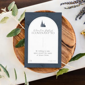 May include: A blue card with a white border and a white temple silhouette. The text on the card reads "When I am Baptized I COVENANT TO" and "Be willing to take upon myself the name of Jesus Christ. 2 Nephi 31:13".