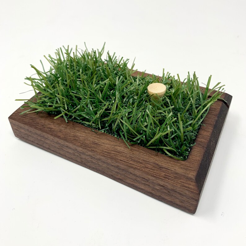 The golf scorecard a ball display holder is a handcrafted walnut display designed to showcase a golf ball and scorecard from your personal best round or hole-in-one. Featuring realistic fake grass under the golf ball on a tee, it’s a perfect way to commemorate your golfing achievements. Ideal for Father's Day, graduations, retirements, or golf trips, this unique gift is a stylish addition to any golfer’s home or office and makes a thoughtful gift for golf enthusiasts.