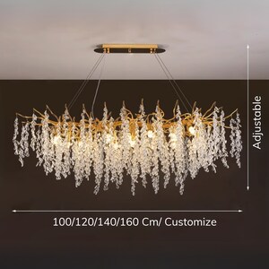 May include: Gold chandelier with crystal drops, featuring a branch-like design. The chandelier is adjustable in length, with options for 100, 120, 140, or 160 cm, or can be customised.