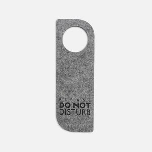 May include: Grey felt door hanger with a round hole at the top and the text "PLEASE DO NOT DISTURB" in black.