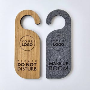 May include: Two door hangers, one wooden and one grey felt. Both feature a circle with the text "Your Logo" and a message. The wooden hanger says "Please Do Not Disturb" and the grey felt hanger says "Please Make Up Room".