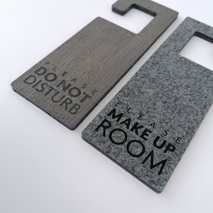 Puede incluir: Dos colgadores de puerta, uno gris y otro marrón, con texto negro. El colgador gris dice "Por favor, haga la habitación" y el colgador marrón dice "Por favor, no molestar".