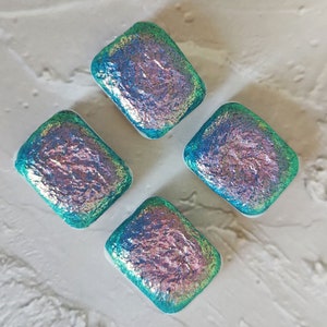 May include: Four iridescent glass tiles in a square shape with a teal blue and pink color scheme.
