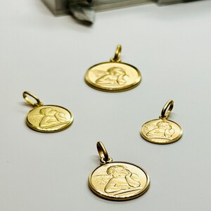 May include: Four gold angel pendant charms of varying sizes. Each charm features a detailed depiction of an angel with wings and a cherubic face.