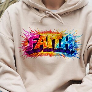 May include: A beige hooded sweatshirt featuring the word "FAITH" in a vibrant, graffiti-style design. The word is in bold, 3D lettering with a colourful gradient of pink, orange, yellow, and blue. The design has a splash effect.