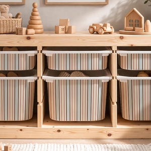 May include: A wooden toy storage unit with six striped bins. The unit is filled with wooden toys, including a car, blocks, and a house. A woven rug and framed art pieces complete the nursery decor.