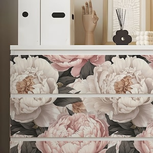 May include: Four drawers of a dresser with a floral pattern. The drawers are white with a black floral pattern of pink and white peonies.