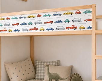 May include: A white adhesive border strip featuring a repeating pattern of colorful illustrated vehicles including cars, trucks, and vans in shades of red, blue, yellow, green, and grey, applied to the top rail of a light-colored wooden bunk bed.