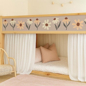 May include: A wooden bunk bed with a floral border. The bed has white curtains, pink pillows, and a pink rug. A wooden chair with a woven seat is in the corner. The floral border features flowers in white, peach, and brown.