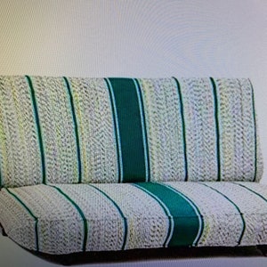 May include: A sofa bed featuring a textured, off-white fabric with a woven pattern. The upholstery is accented by vertical stripes in dark green and thin lines of yellow and blue. The design includes a wide, solid dark green center panel.